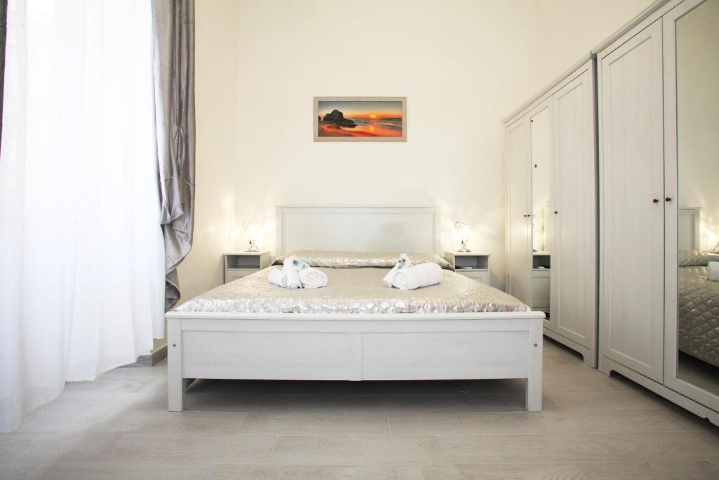 ein weißes Schlafzimmer mit einem Bett mit Handtüchern darauf in der Unterkunft Brillante Appartamento di Sara in Anzio