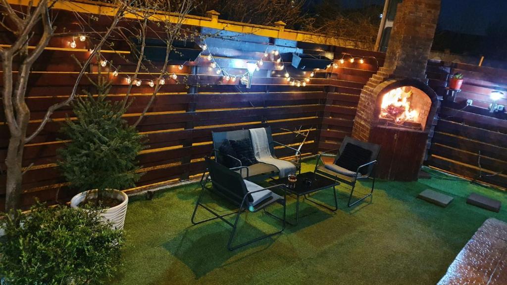 a patio with chairs and a fireplace at night at Cozy villa, close to the center of Bucharest. in Bragadiru