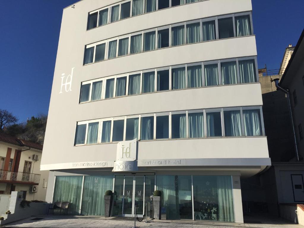 a tall white building with glass windows at Hotel iDesign in San Marino