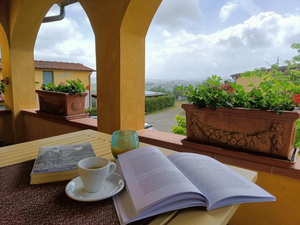 um livro aberto e uma chávena de café numa mesa com uma janela em La Loggia del Ciliegio in Chianti em Montespertoli