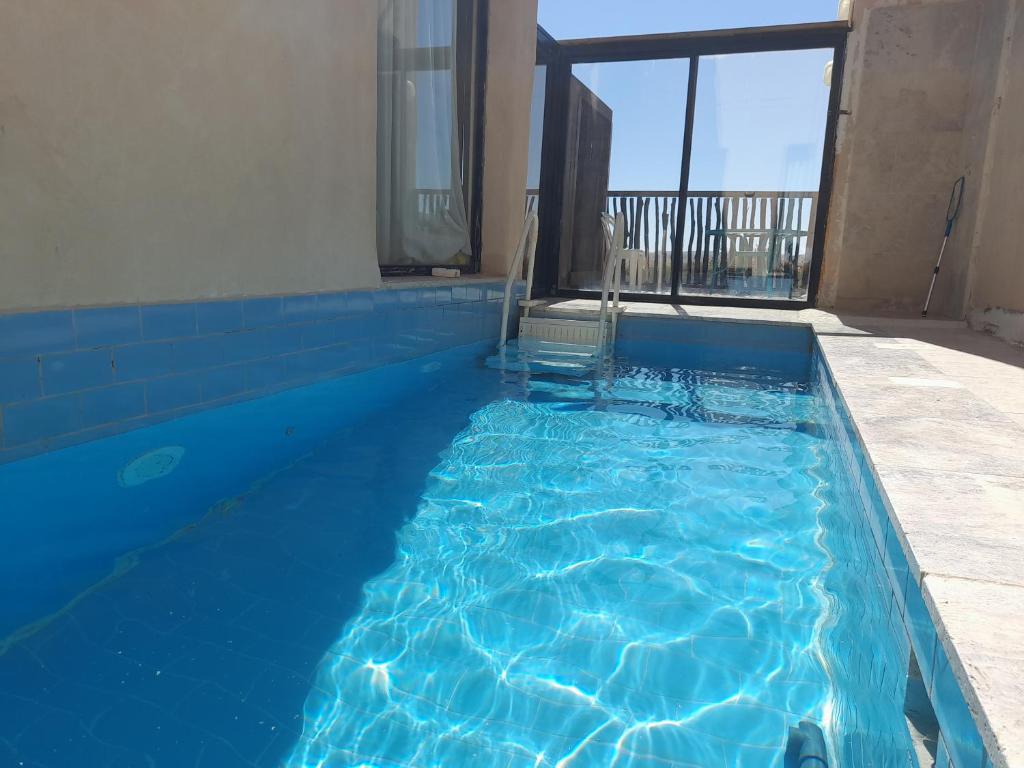 una piscina de agua azul en un edificio en שיח מדבר לינה בנגב Burning Bush Negev, en Merhav Am