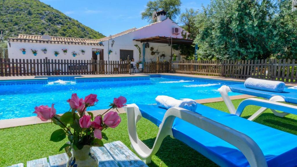 una piscina con 2 sillas y una casa en Cortijo Palitroques Carcabuey by Ruralidays, en Carcabuey