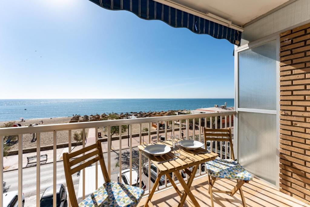 een balkon met een tafel en stoelen en het strand bij Ventana al mar in Fuengirola