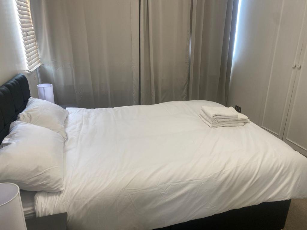 ein weißes Bett mit zwei Handtüchern darüber in der Unterkunft Cozy two bedroom flat in the heart of London in London