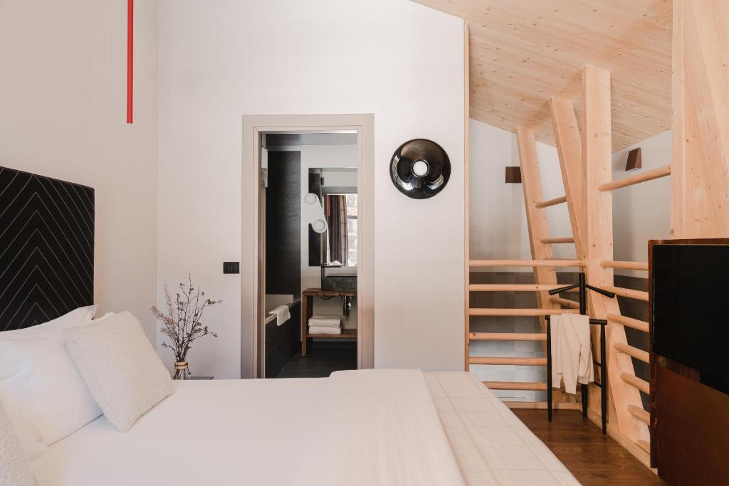 a bedroom with a white bed and a wooden staircase at Aethos Monterosa in Champoluc