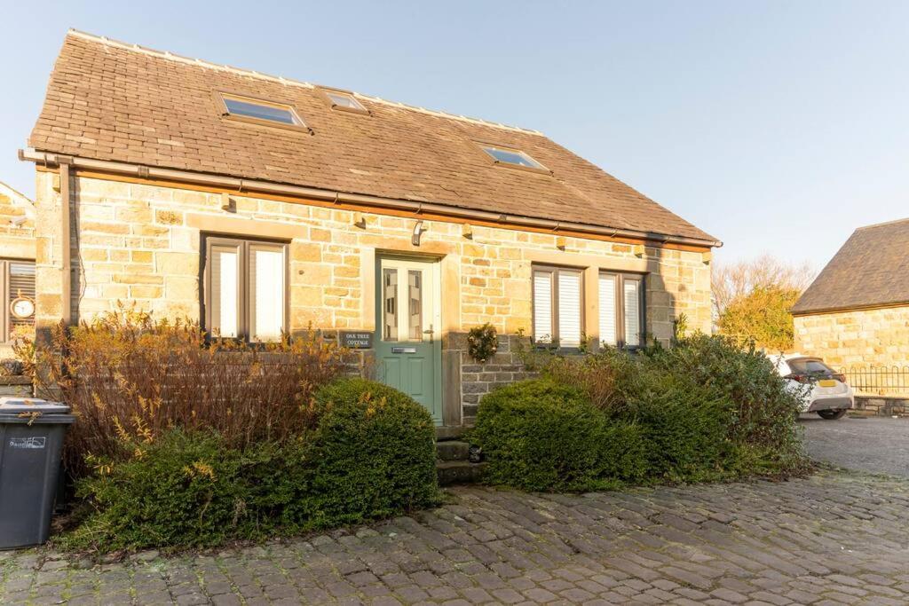 een stenen huis met een groene deur in een straat bij Oak Tree Cottage - Pendle - Forest of Bowland in Burnley