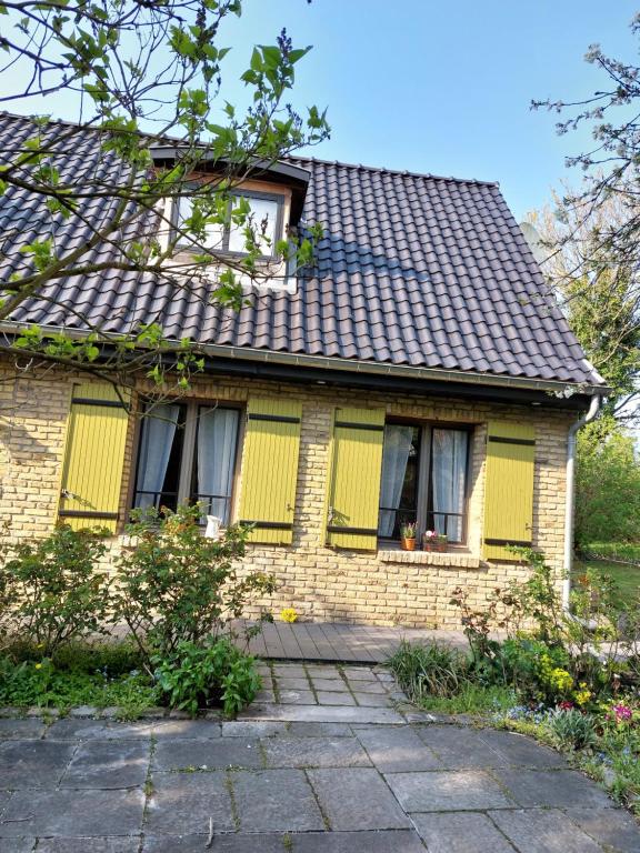 a brick house with yellow shutters on it at Ô Chambres d'Hôtes 