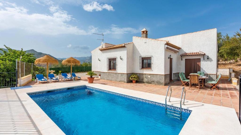 a villa with a swimming pool in front of a house at Cortijo Sylvestris Periana by Ruralidays in Periana