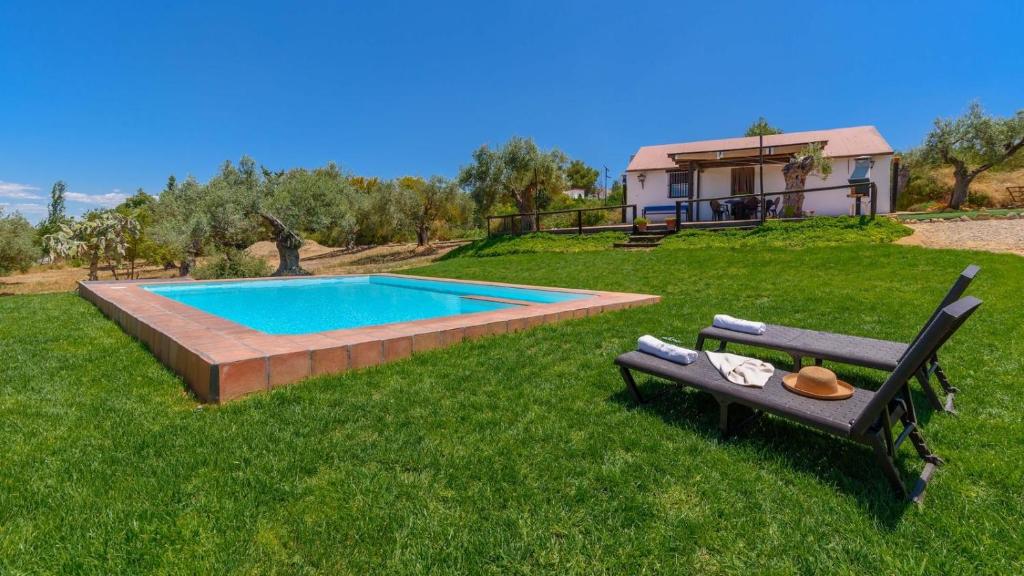 a pool in a yard with a bench and a house at La Marchoza Aznalcázar by Ruralidays in Aznalcázar