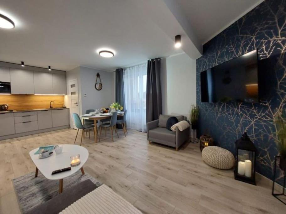 a living room with a couch a table and a kitchen at Baltic Sands Apartment Darłówko Wschodnie in Darłowo