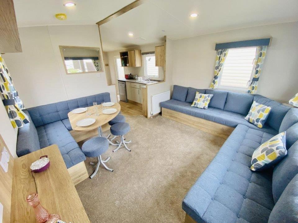 ein Wohnzimmer mit einem blauen Sofa und einem Tisch in der Unterkunft Arizona - Pura Vida Holidays Caravan in Clacton-on-Sea