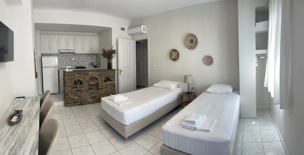 ein Wohnzimmer mit 2 Betten und eine Küche in der Unterkunft Manto Apartments in Tinos