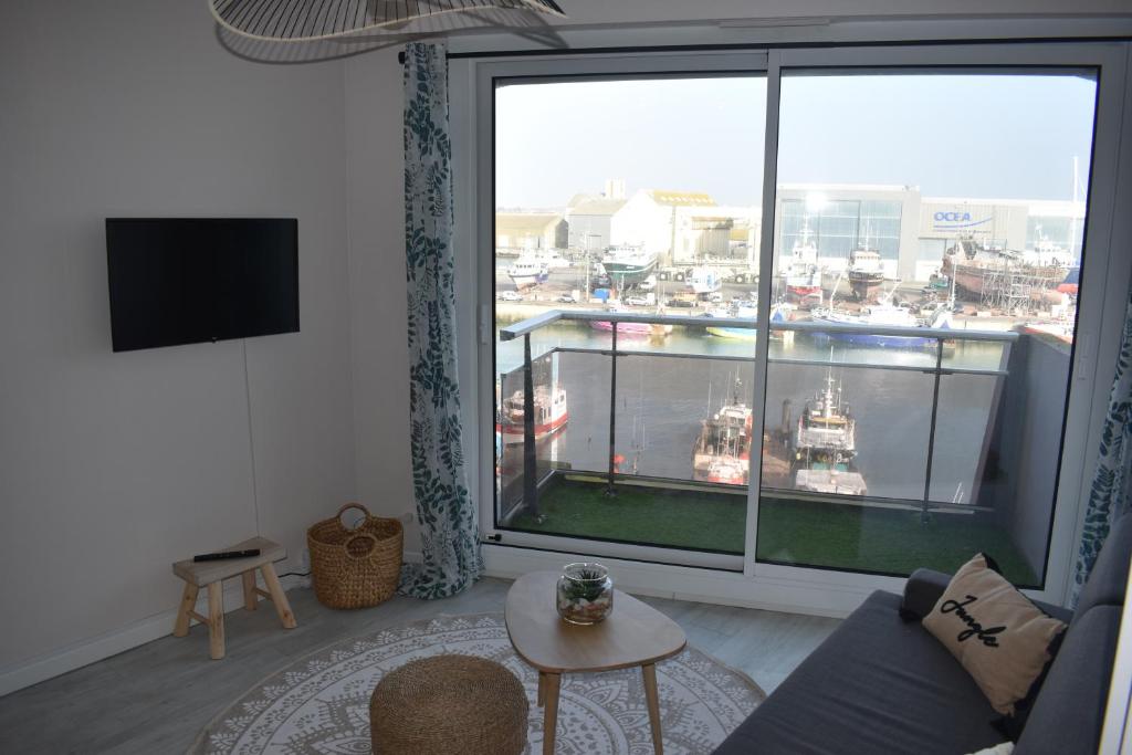 a living room with a large window with a view of a harbor at Studio, vue exceptionnelle sur le port de pêche in Les Sables-d&#39;Olonne
