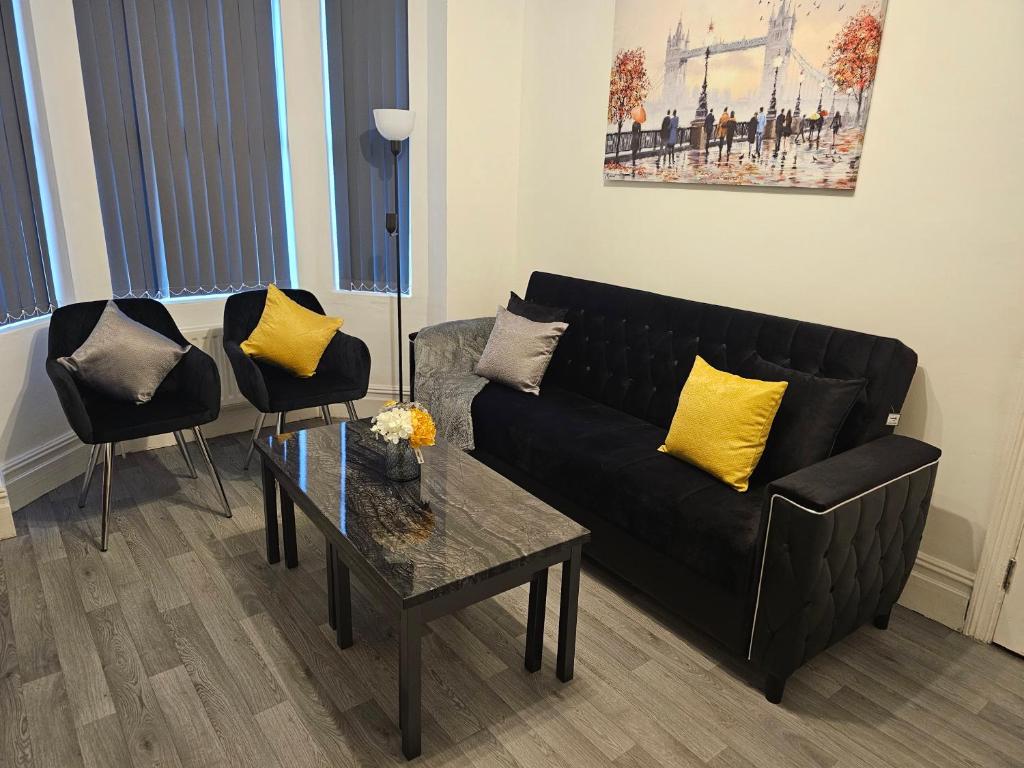 a living room with a black couch and yellow pillows at SAV Apartments - Russell, Luton (4 Bed House) in Luton