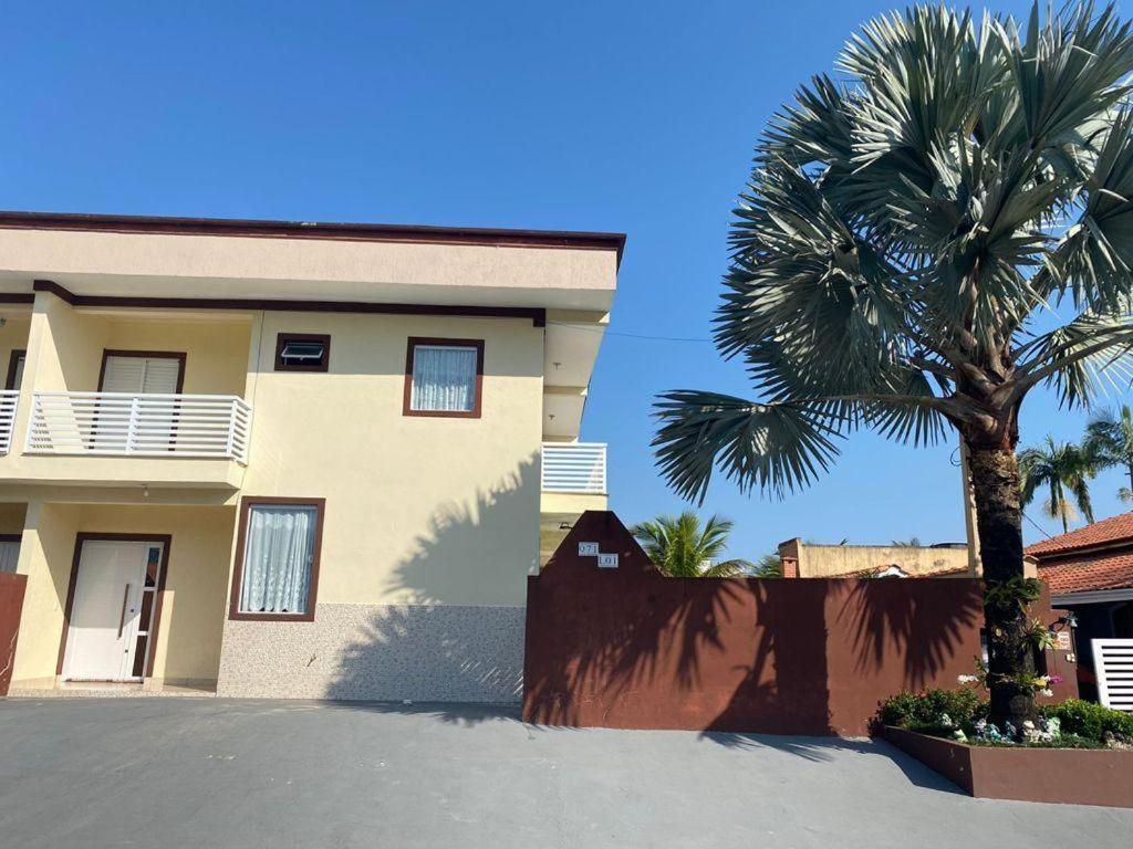 een gebouw met een palmboom ervoor bij Beachouse Marissol Morada da Praia in Bertioga
