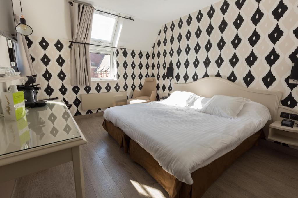 a bedroom with a bed with a black and white patterned wall at Cit'Hotel - Hotel Le Cèdre in Noyon