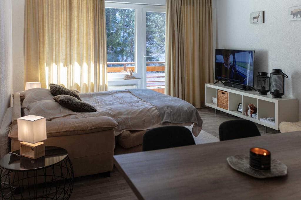 - une chambre avec un lit, une télévision et une table dans l'établissement Grand Studio au centre de Crans, à Crans-Montana