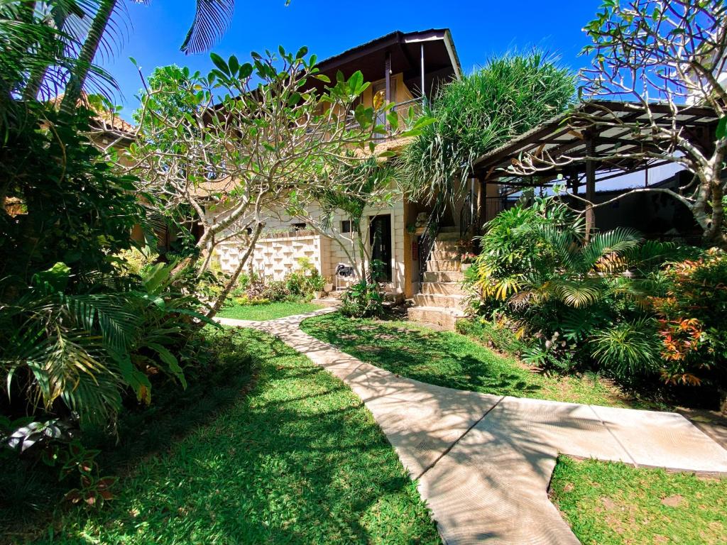 a walkway leading to a house with trees and plants at Home-Bience Hostel in Uluwatu