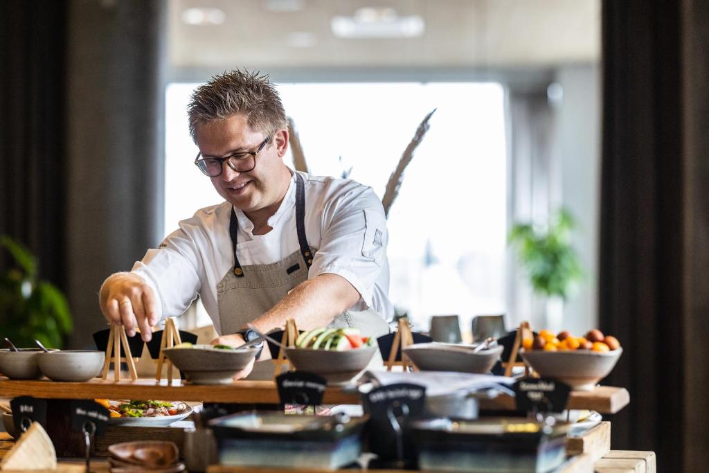a man preparing food on a table with chopsticks at Aalborg Airport Hotel in Aalborg