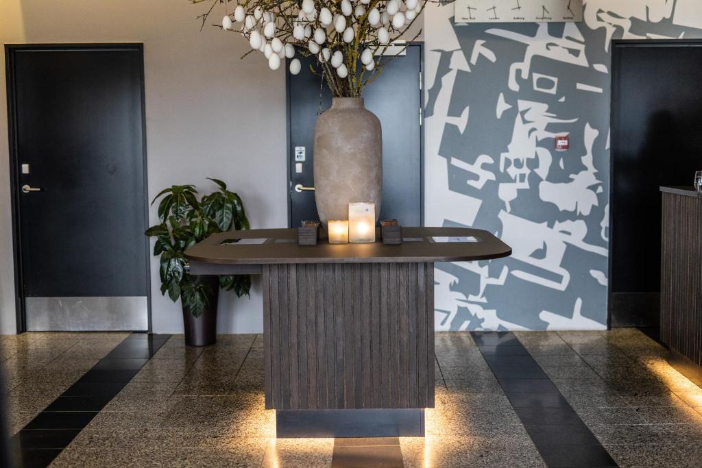 a table in a lobby with a vase on the wall at Aalborg Airport Hotel in Aalborg