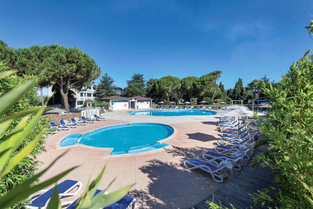 a swimming pool with chaise lounges and chairs at Belambra Clubs Balaruc-les-Bains - Les Rives De Thau in Balaruc-les-Bains