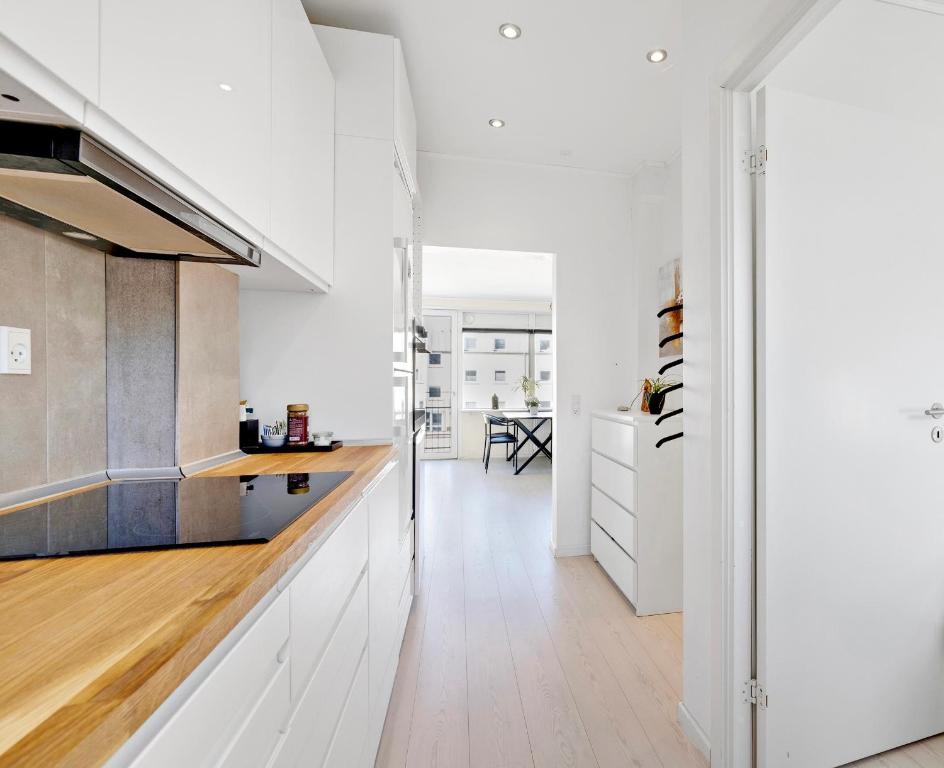 a kitchen with white cabinets and wood floors at Privat, skandinavisk og moderne lejlighed - med gratis parkering in Randers