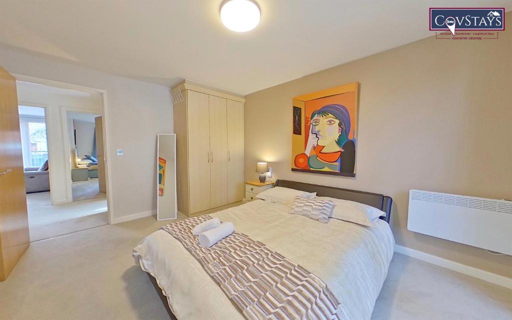 a bedroom with a large bed with a painting on the wall at Triumph House - 3 bed 2 bath Apartment in Coventry City Centre, sleeps 6, Free secured parking, balcony, by COVSTAYS in Coventry