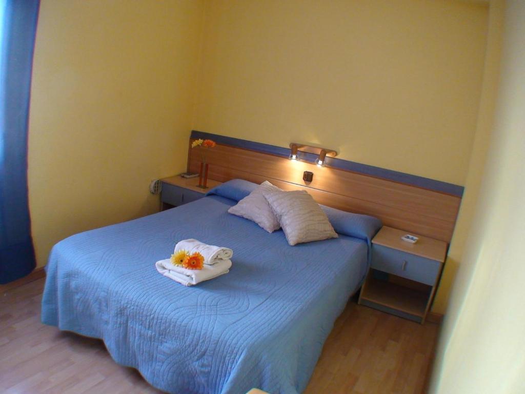 a bedroom with a blue bed with two towels on it at Hostal El Carmen in Zaragoza