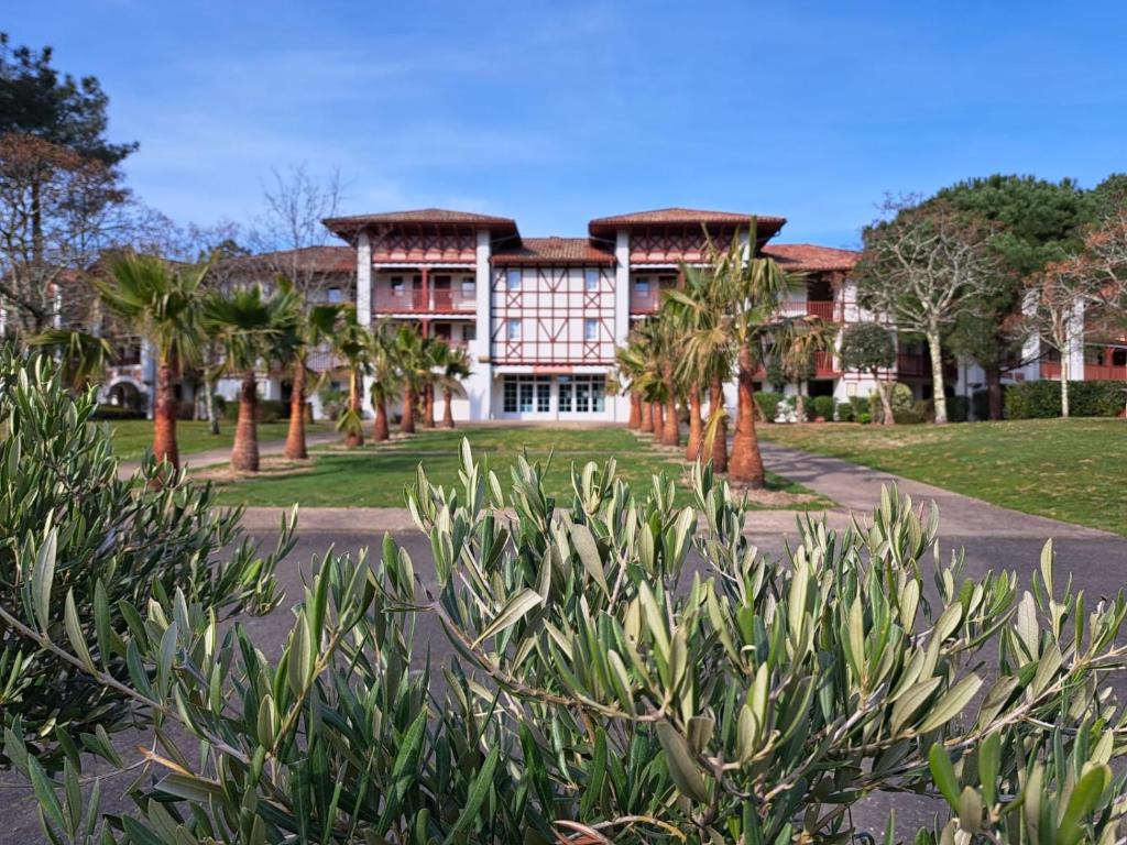 uma casa grande com palmeiras em frente em Appart-dans Résidence de vacances au coeur du Golf-Le domaine de Gascogne em Biscarrosse