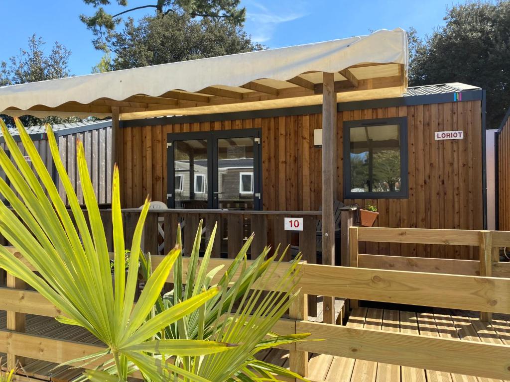 a tiny house with a roof on a wooden deck at Camping Le Repos in Saint-Palais-sur-Mer