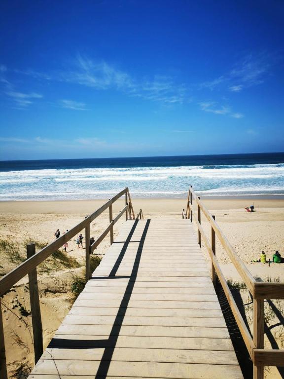 - une promenade en bois menant à une plage avec des personnes y séjournant dans l'établissement Cottage chaleureux Louann, à Labouheyre