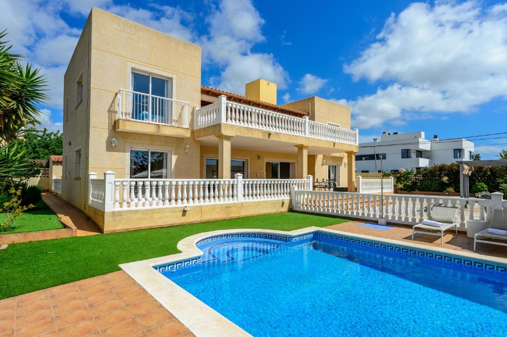 a villa with a swimming pool in front of a house at Villa next to playa Bossa in Sant Josep de sa Talaia