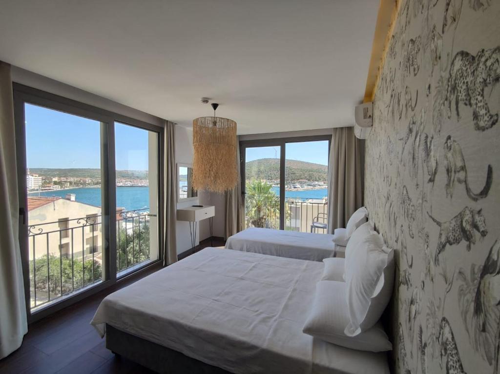 a bedroom with two beds and a large window at Eva Otel Çeşme in Cesme