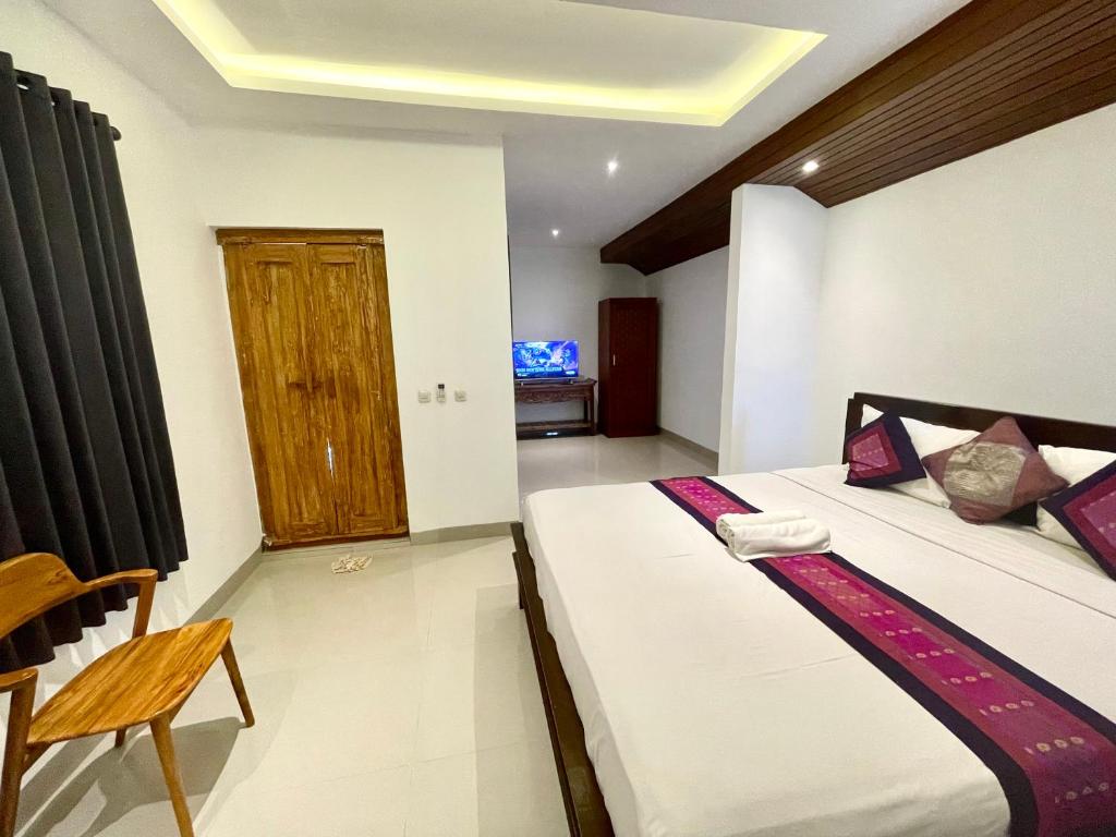 a bedroom with two beds and a wooden door at DIMUWA Ubud in Ubud