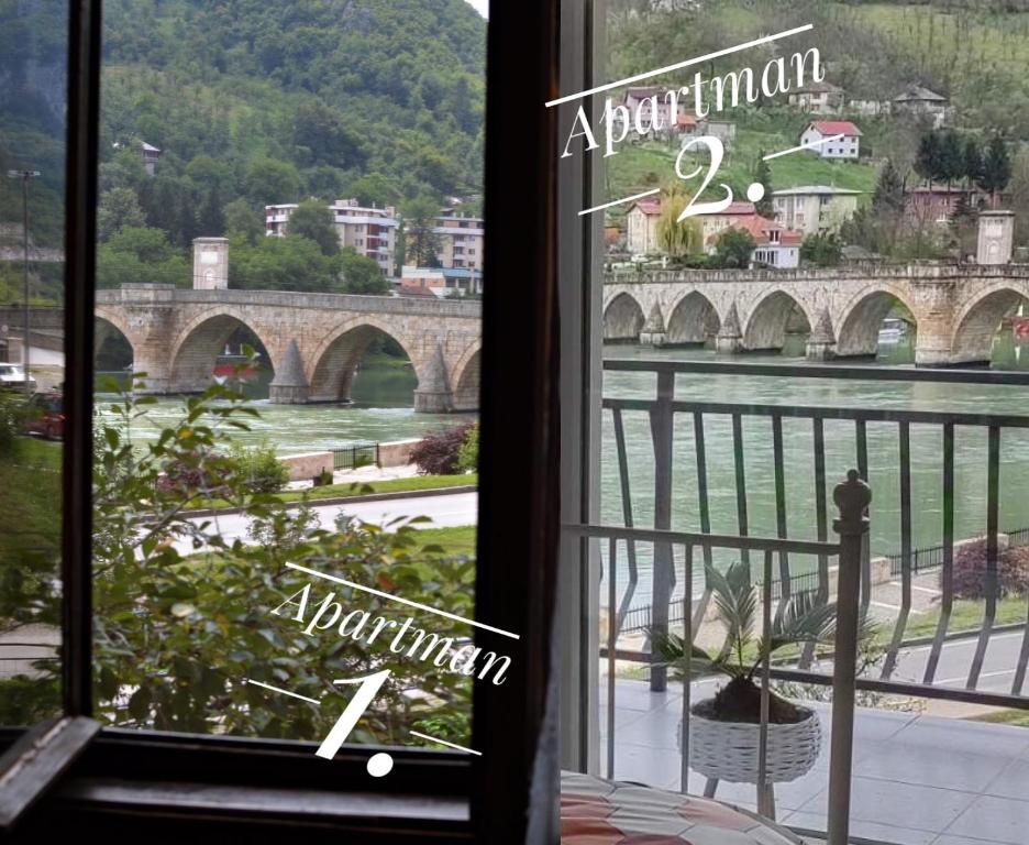 une fenêtre avec vue sur une rivière et un pont dans l'établissement Ive Andrica 3, à Višegrad