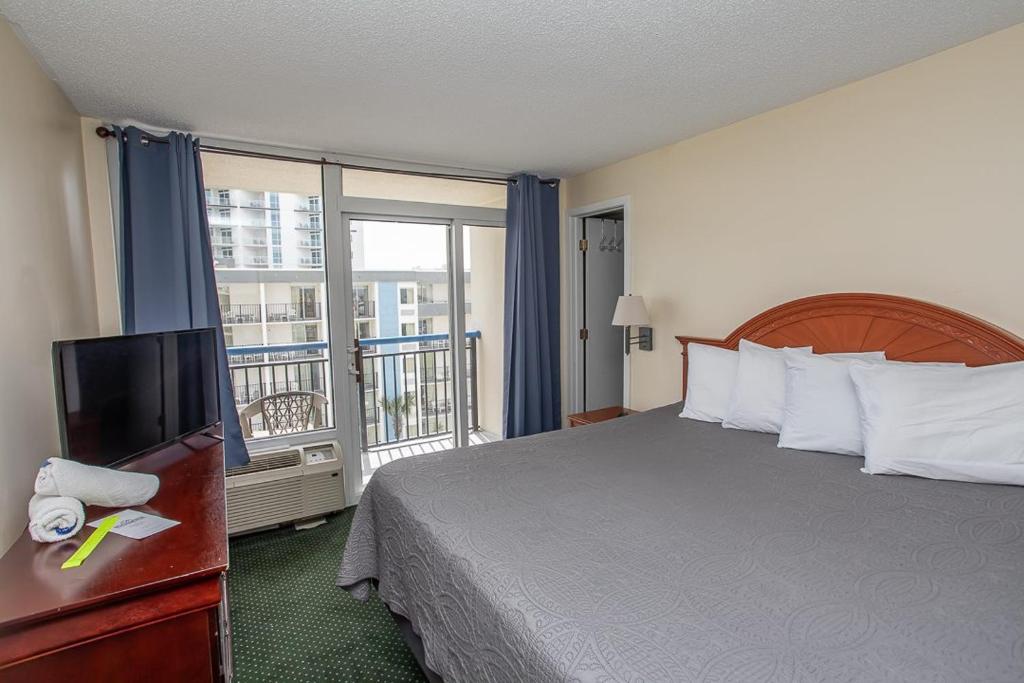 ein Hotelzimmer mit einem Bett und einem Flachbildfernseher in der Unterkunft Ocean View Studio King Suite Boardwalk Resort Unit 540 Sleeps 2 in Myrtle Beach