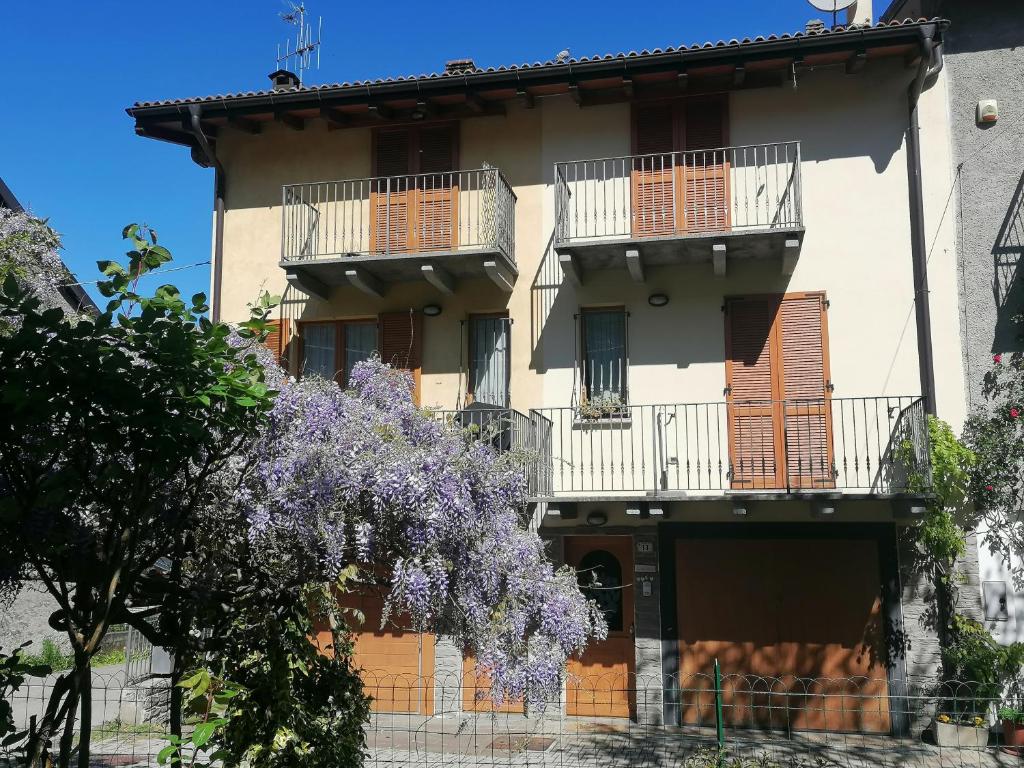 a building with balconies and a tree with purple flowers at CASA DELLA VALLE in Colico