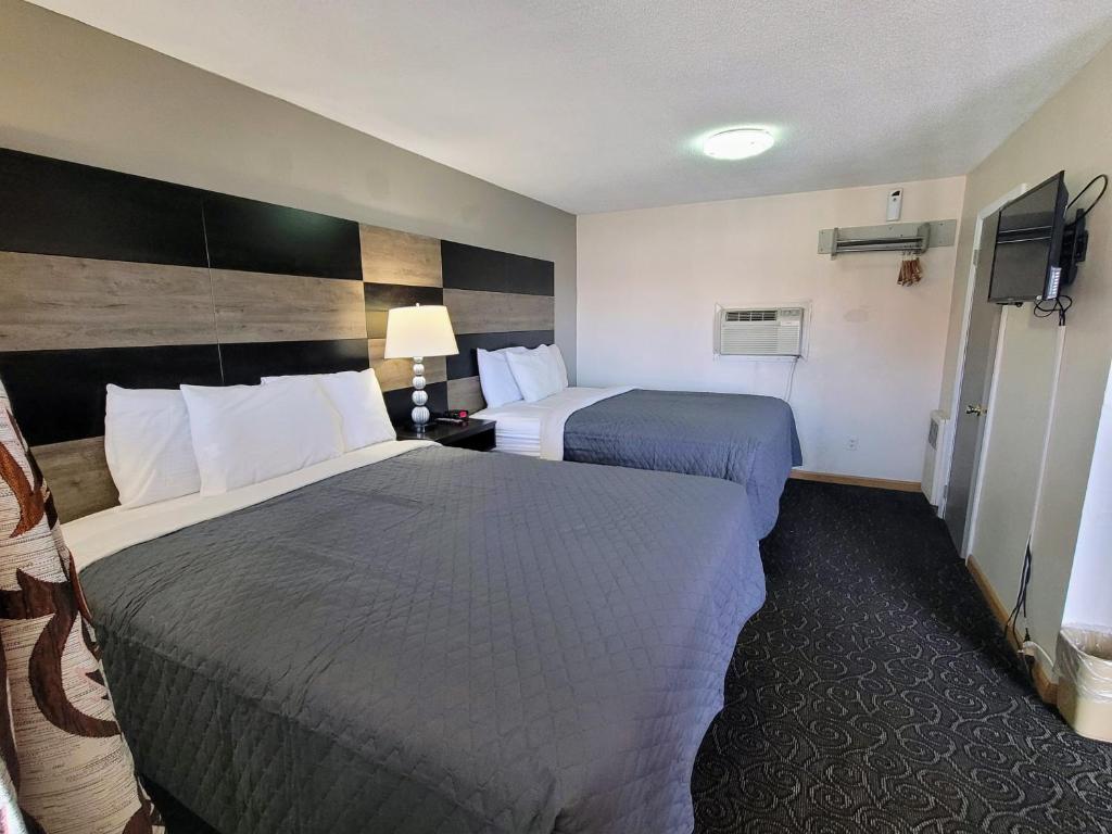 a hotel room with two beds and a television at Woodland Inn in Niagara Falls