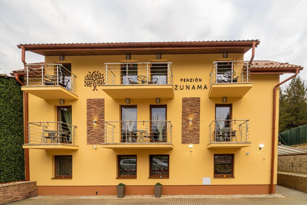 um edifício amarelo com varandas em Penzión Zunama em Bardejovské Kúpele