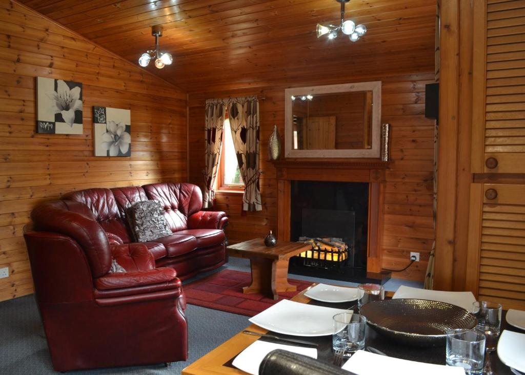 a living room with a leather couch and a fireplace at Beechwood Park in Shardlow
