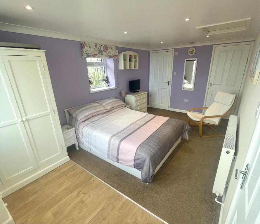 a bedroom with purple walls and a bed and a chair at Y Villa Môr in Llanarth