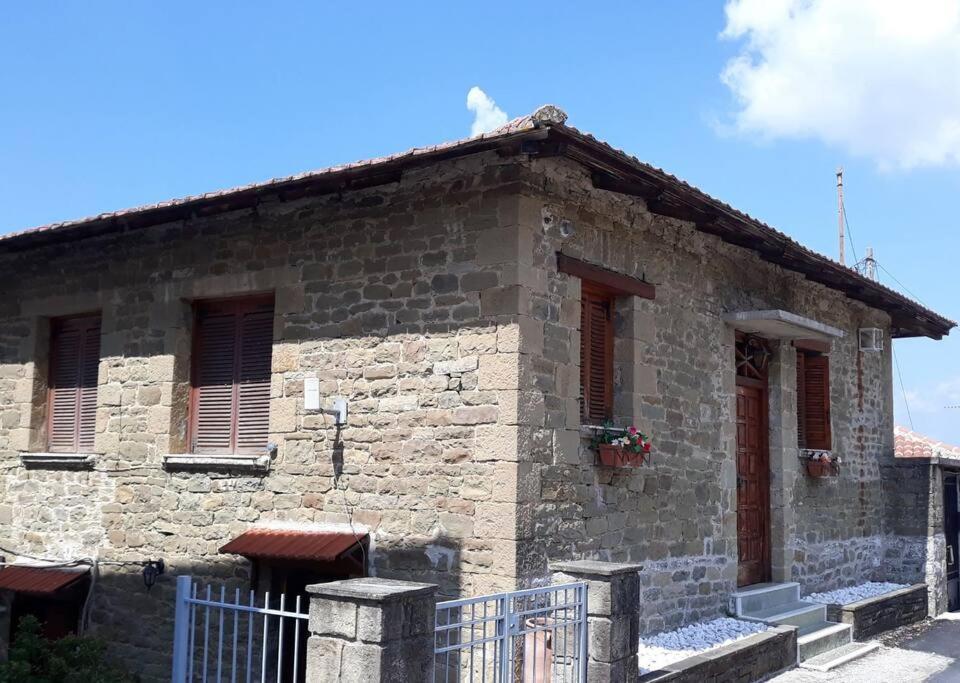 uma casa de pedra com uma cerca em frente em Melissomandri - traditional house at Kompoti 