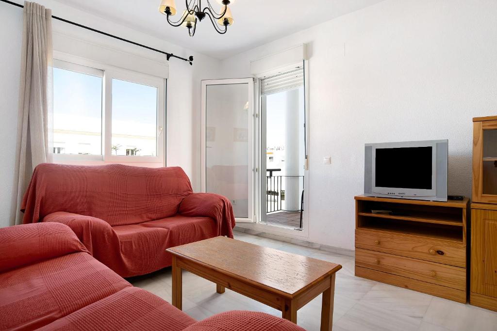 sala de estar con sofá rojo y TV en Piso Fábrica - Solo Familias, en Conil de la Frontera