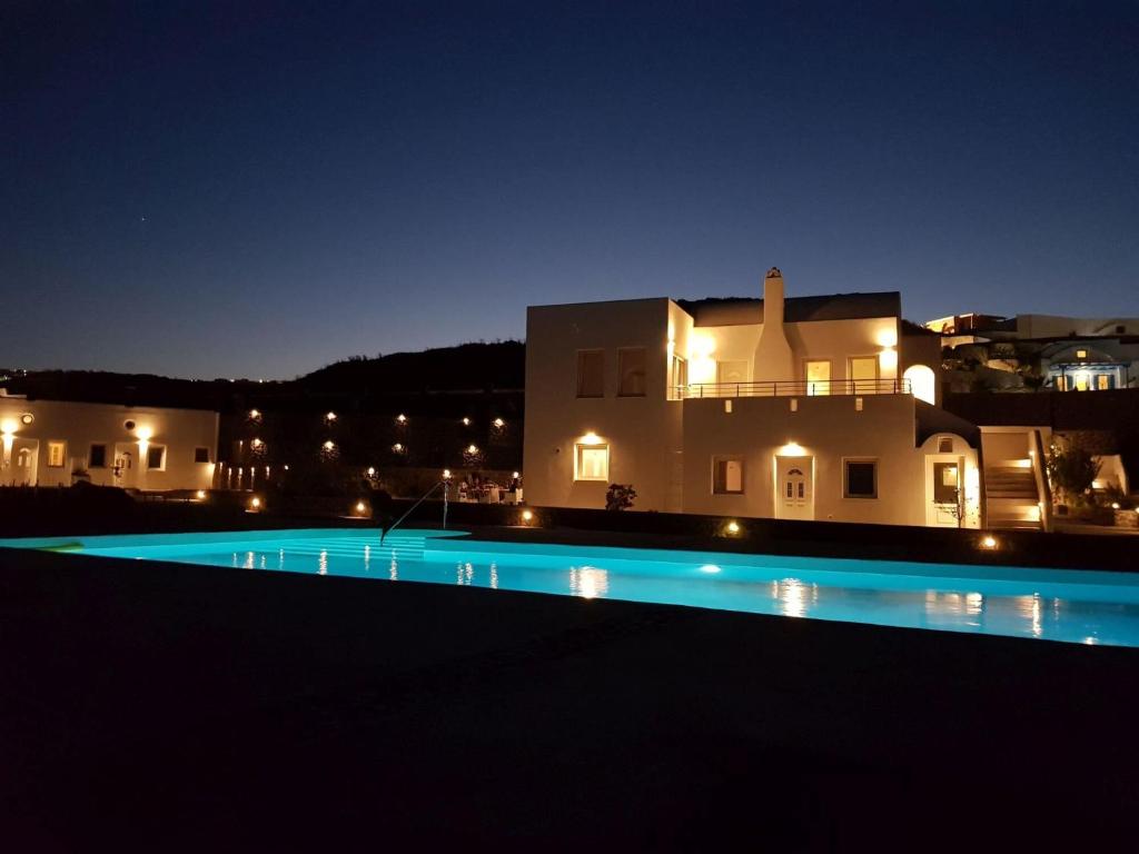 a night view of a swimming pool in front of a house at Villas Scirocco in Fira