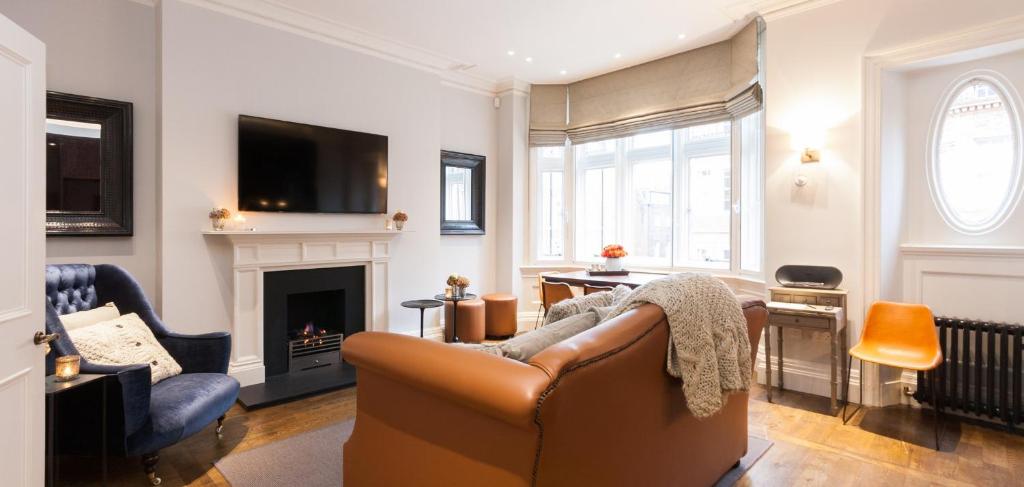 ein Wohnzimmer mit einem Sofa und einem Kamin in der Unterkunft The Chesterfield Suite in London