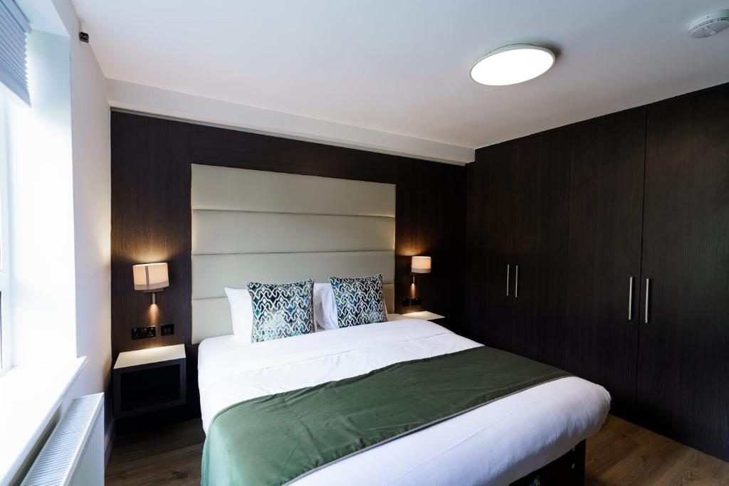 a bedroom with a large bed with dark wood cabinets at Penywern Apartment Earls Court in London