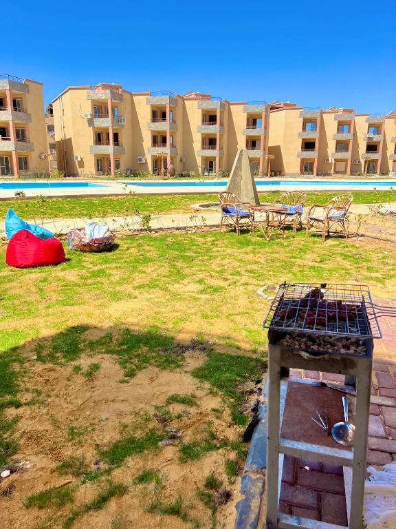 a yard with chairs and a grill in front of a building at Chalet in La Jolie Marina El Ain El Sokhna - Egyptian Families Only in Ain Sokhna