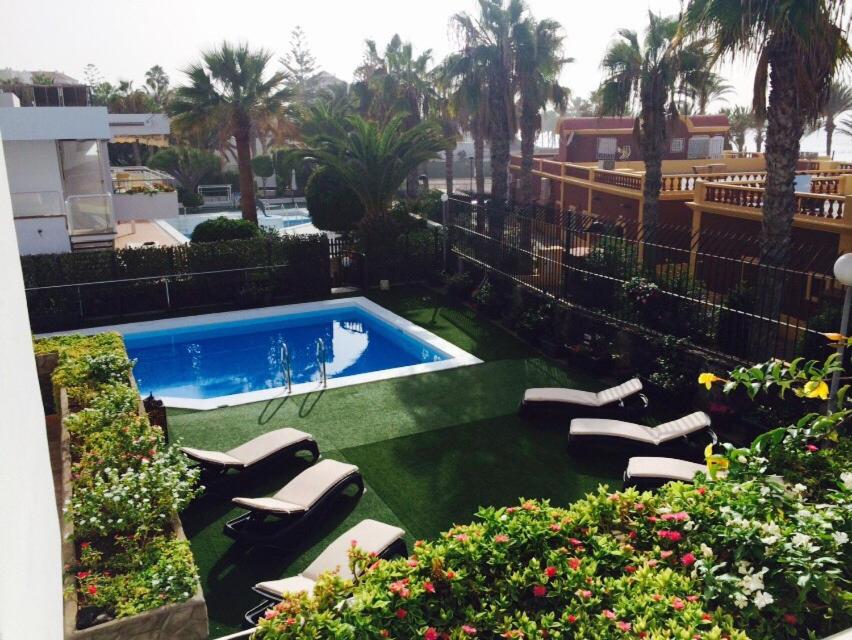 a swimming pool with lounge chairs in a yard at Villa Las Americas in Playa de las Americas