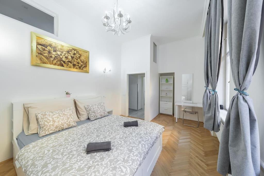 - une chambre blanche avec un lit et un lustre dans l'établissement Opletal Apartment, à Prague