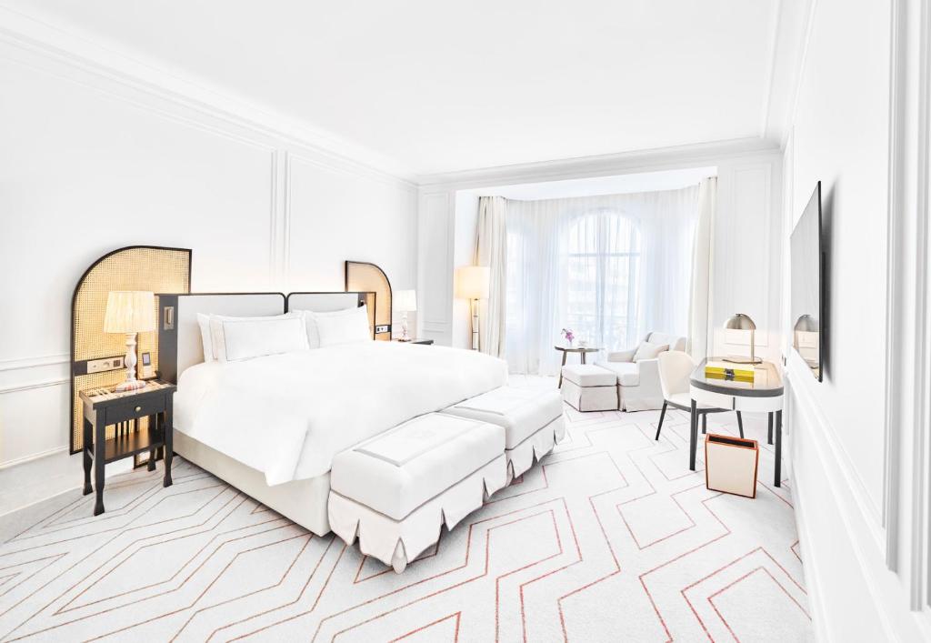 a white bedroom with a large bed and a couch at Carlton Cannes, a Regent Hotel in Cannes